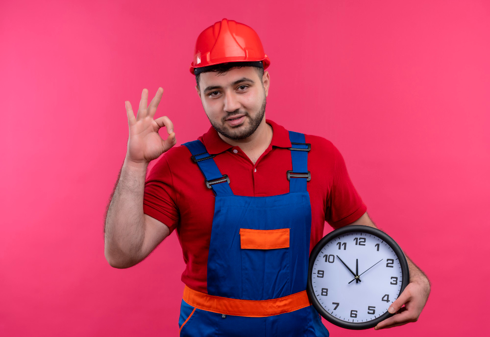 young-builder-man-construction-uniform-safety-helmet-holding-wall-clock-doing-ok-sign-smiling